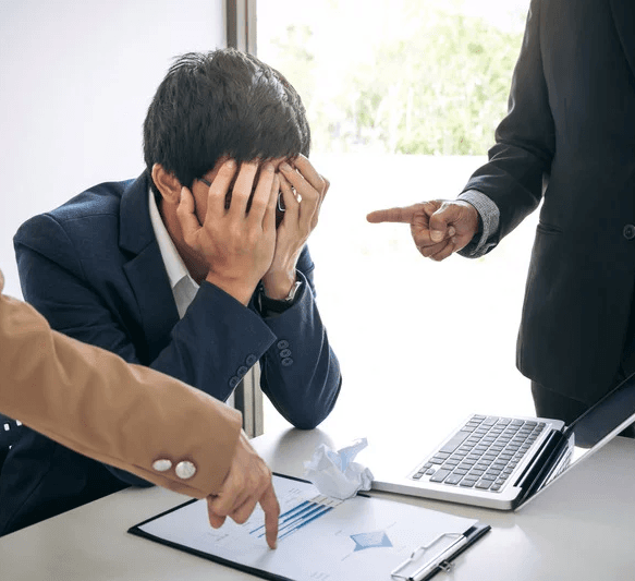 Business professional looking stressed with head in hands during meeting